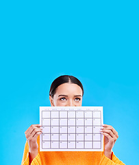 Image showing Calendar, thinking and woman on blue background with paper for schedule, planning and agenda in studio. Time management, strategy and eyes of girl with month poster for date, weekly planner and event