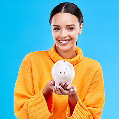 Image showing Happy woman, money and piggy bank for investment, budget or finance against a blue studio background. Portrait of female smile holding savings, cash or coin for profit, investing or financial freedom