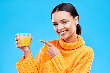 Image showing Happy woman, portrait and pointing to orange juice in studio, blue background and backdrop. Female model, drinking glass and fruit cocktail beverage for nutrition, diet and detox health of vitamin c