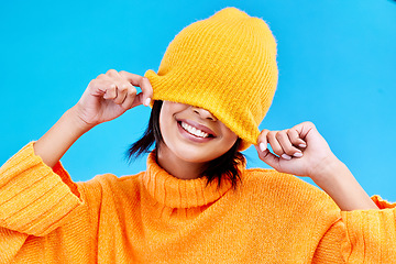 Image showing Fashion, happy and hide with woman and beanie in studio for cover, winter and goofy. Playful, happiness and smile with female and knitted hat isolated on blue background for funny, silly and cool