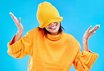 Image showing Fashion, crazy and cover with woman and beanie in studio for hiding, winter and goofy. Playful, happiness and smile with female and knitted hat isolated on blue background for funny, silly and cool