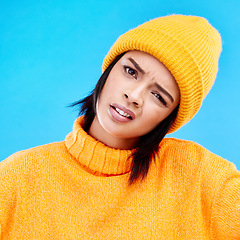 Image showing Portrait of woman in winter fashion with confusion, beanie and doubt isolated on blue background. Style, funny expression on face and gen z girl on studio backdrop with warm clothing for cold weather