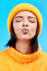 Image showing Portrait of woman in winter fashion with kiss face, beanie and jersey isolated on blue background. Style, flirt and romance, gen z girl in studio backdrop with love and warm clothing for cold weather