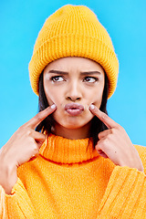 Image showing Quirky, goofy and young female in a studio with a comic, funny and crazy face expression. Gen z, silly and beautiful woman model from Puerto Rico touching her cheeks isolated by a blue background.