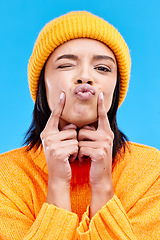 Image showing Portrait of woman in winter fashion with kiss, beanie and happiness isolated on blue background. Style, face of happy gen z girl in studio with fun expression and warm clothing for cold weather.