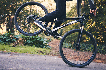 Image showing Closeup man, mountain bike and wheel for cycling stunt in park, nature and path for fitness, cardio and freedom. Bicycle, cyclist and extreme sports athlete training for action, wheelie stunt or risk