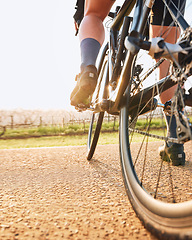 Image showing Bicycle closeup, countryside ride and person on a bike with speed for sports race on a gravel road. Fitness, exercise and athlete legs doing sport training in nature on a trail for cardio and workout