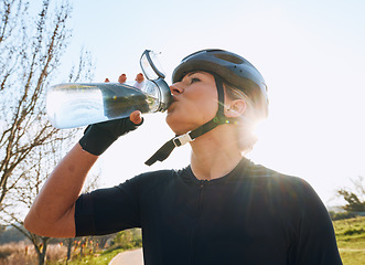 Image showing Woman drinking water, bottle and cycling with fitness outdoor, helmet for safety and health with hydration. Athlete, biking and female with healthy and active lifestyle, wellness and sports training