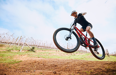 Image showing Bicycle jump, countryside and woman on a bike with speed for sports on a dirt road. Fitness, exercise and fast athlete doing sport training in nature on a park trail for cardio and cycling workout