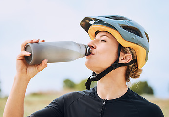 Image showing Woman drinking water, bottle and cycling outdoor with fitness, helmet for safety and health with hydration. Athlete, biking and female with healthy and active lifestyle, drink liquid and training