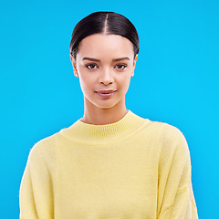 Image showing Portrait, serious and woman in studio, relaxed and confident against a blue background. Face, pose and young female smile, relax and standing on isolated space, mockup and indoor product placement