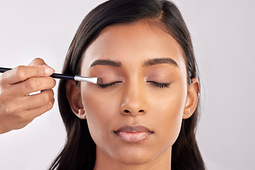 Image showing Woman, face and makeup for eyes with brush and beauty, beautician and cosmetics tools on studio background. Cosmetology, facial and skin glow with young Indian female, eyeshadow and cosmetic care