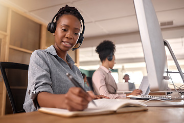 Image showing Call center, woman and writing at computer on desk in office for sales and customer service notes and information, African female agent or consultant in telemarketing, support and crm with notebook