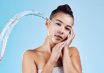 Image showing Portrait, beauty and woman with water splash, cosmetics and cleaning against a blue studio background. Face, female model and person with drops, wellness and morning routine for self care and health