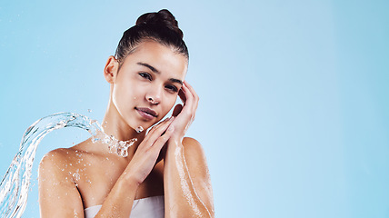 Image showing Portrait, dermatology and woman with water splash, cleaning and beauty on a blue studio background. Face, female and person with clear liquid, morning routine and cosmetics for wellness and self care