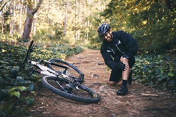 Image showing Sports man, injury and leg pain outdoor while cycling on mountain bike with nature trees and dirt. Athlete person on ground in forest for fitness exercise, training or workout accident, crash or fall