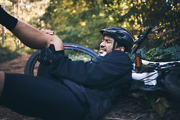 Image showing Man, cycling injury and leg or knee pain outdoor on mountain bike in nature. Athlete person on forest ground for fitness exercise or training workout accident, crash or fall with helmet and bicycle