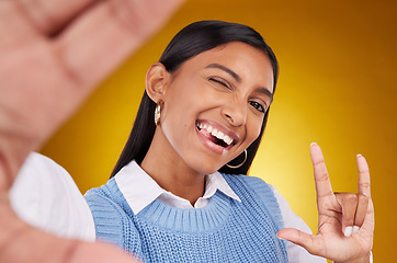 Image showing Selfie, rock sign and portrait of Indian woman in studio for happiness, confident and wink on yellow background. Mockup, fashion and girl with punk hand gesture with beauty, cosmetics and makeup