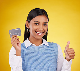 Image showing Credit card, thumbs up and portrait of Indian woman on yellow studio for bank, investment and payment. Banking mockup, finance and happy girl with yes hand sign for budget, commerce and purchase