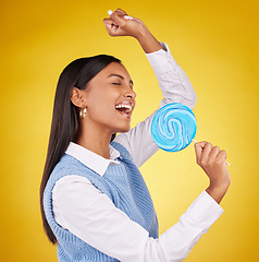 Image showing Candy, sing and woman with lollipop, happy and cheerful against a studio background. Female, excited and girl with sweets, dessert and happiness with treat, freedom and wellness with joy and positive