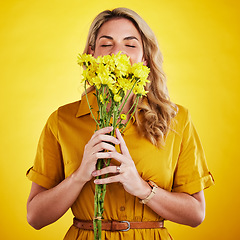 Image showing Portrait, smelling and woman with flowers in studio isolated on a yellow background. Floral, bouquet and person sniff, aroma or scent with female model holding natural plants and fresh flower.