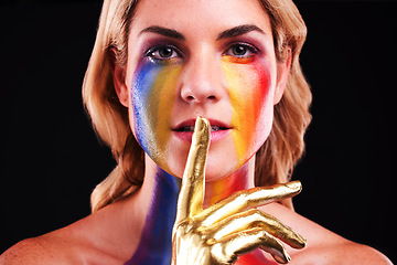 Image showing Woman, metallic portrait and beauty secret with color paint cosmetics on skin and face in studio. Female model on a black background for gold art, fantasy and creative makeup with finger on lips