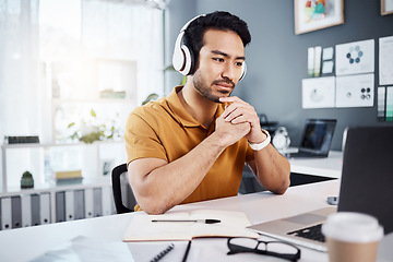 Image showing Thinking, laptop and headphones on business man listening to music, audio or webinar. Asian male entrepreneur with technology for planning strategy, idea or reading email or communication on internet