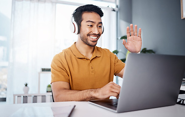 Image showing Headphones, laptop and man on video call, webinar or virtual meeting, talking and online in work from home office. Happy Asian person waves hello on his computer pc in client chat for tech business