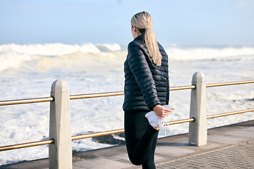 Image showing Stretching legs, fitness and a woman at the beach for running, exercise and getting ready for cardio. Back, ocean and a runner preparing to train for sport or an outdoor workout with a warm up