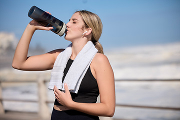 Image showing Fitness, music and woman drinking water at the beach for sports, running and cardio routine. Podcast, bottle and thirsty female runner relax on workout break while streaming online motivation track