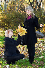 Image showing Two beautiful young women with autumn leaves in park