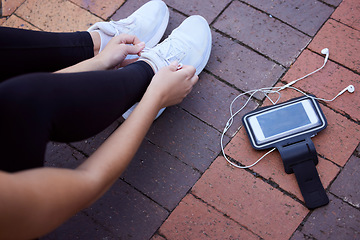 Image showing Phone, fitness and footwear from above with a woman athlete sitting on the ground to tie laces. Exercise, music and getting ready for running with a female sports person outdoor for cardio training