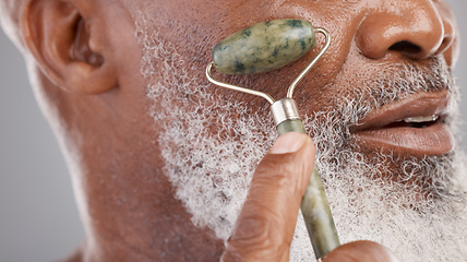 Image showing Face roller, closeup and senior man with skincare, stone and dermatology product for skin glow. Elderly, cheek and facial roll of African male model doing self care for grooming with jade for beauty