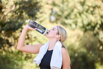 Image showing Fitness, runner or girl drinking water in park to hydrate, relax or healthy energy on exercise break in nature. Tired thirsty athlete woman refreshing with liquid for hydration in training or workout