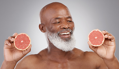 Image showing Senior black man, grapefruit and smile for skincare, natural nutrition or vitamin c against a gray studio background. Happy African American male holding fruit for healthy skin, diet or wellness