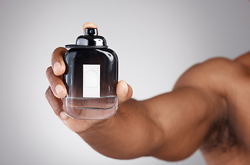 Image showing Hand, bottle and cologne with a man in studio on a gray background holding a perfume fragrance product. Luxury scent, glass and spray with a male showing a container of cosmetics for a fresh smell