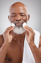 Image showing Skincare, cotton pads and black man with facial cleansing, anti ageing spa treatment on white background. Dermatology, cosmetic process and mature male model with luxury cleaning routine in studio.