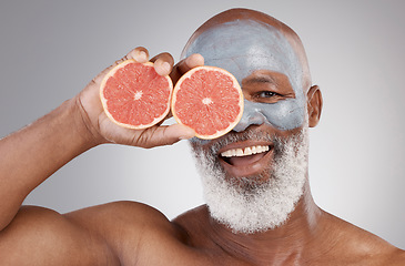 Image showing Senior black man, grapefruit and smile in skincare, vitamin C or natural nutrition against gray studio background. Portrait of happy African male with fruit and face mask for healthy skin or wellness