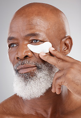 Image showing Skin care, collagen eye mask and black man with hand on face on studio background for professional anti ageing spa treatment. Dermatology, cosmetic process and mature model with skincare on eyes.