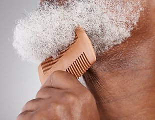 Image showing Man, hands and beard with comb in grooming, beauty or skincare hygiene against a studio background. Closeup of senior male neck and chin combing or brushing facial hair for clean wellness or haircare