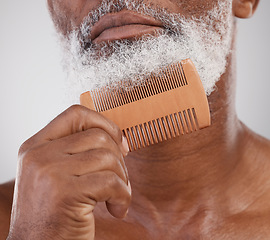 Image showing Man, hands and comb on beard for grooming, beauty or skincare hygiene against a studio background. Closeup of senior male neck and chin combing or brushing facial hair for clean wellness or haircare