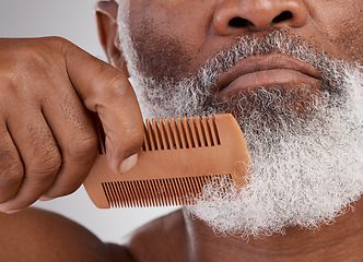 Image showing Senior black man, hands and beard with comb in grooming, beauty or skincare hygiene against a studio background. Closeup of African elderly male face combing or brushing facial hair in clean wellness