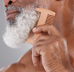 Image showing Man, hands and closeup of beard with comb in grooming, beauty or skincare hygiene against a studio background. Senior male neck and chin combing or brushing facial hair for clean wellness or haircare