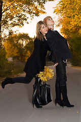 Image showing Two beauty young blondes with autumn leaves on a road