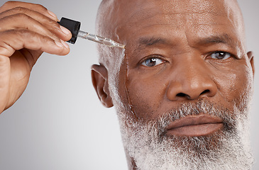 Image showing Skincare, portrait and male with face oil in a studio for a natural, beauty and skin treatment. Cosmetic, health and senior man model with facial serum for a wellness routine by a gray background.