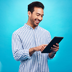 Image showing Tablet, man and smile in a studio on social media, internet and website app scroll. Happiness, isolated, and blue background with a male model reading a ebook on a digital networking application