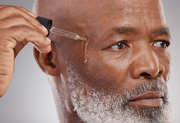 Image showing Skincare, self care and man with face serum in a studio for a natural, beauty and skin treatment. Cosmetic, health and senior male model with facial oil for a wellness routine by a gray background.