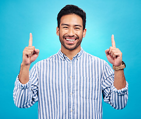 Image showing Point, happy and portrait of Asian man on blue background for news, information and announcement. Advertising, studio mockup and face of excited male pointing for copy space, promo and showing sign