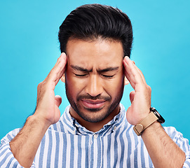 Image showing Man with headache, pain and stress with anxiety and mental health problem or crisis isolated on blue background. Male person hands holding head, massage temple with depression and migraine in studio