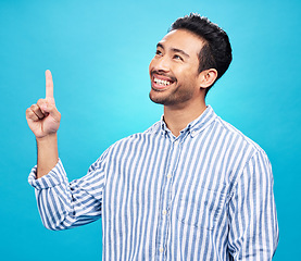 Image showing Point, thinking and man on blue background for news, information and announcement in studio. Advertising, mockup sign and face of excited male pointing for copy space, promotion and showing gesture